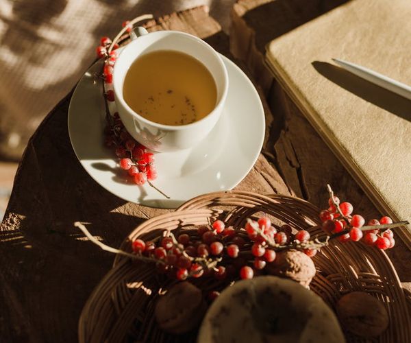 A cup of herbal tea on a wooden table next to a notebook.